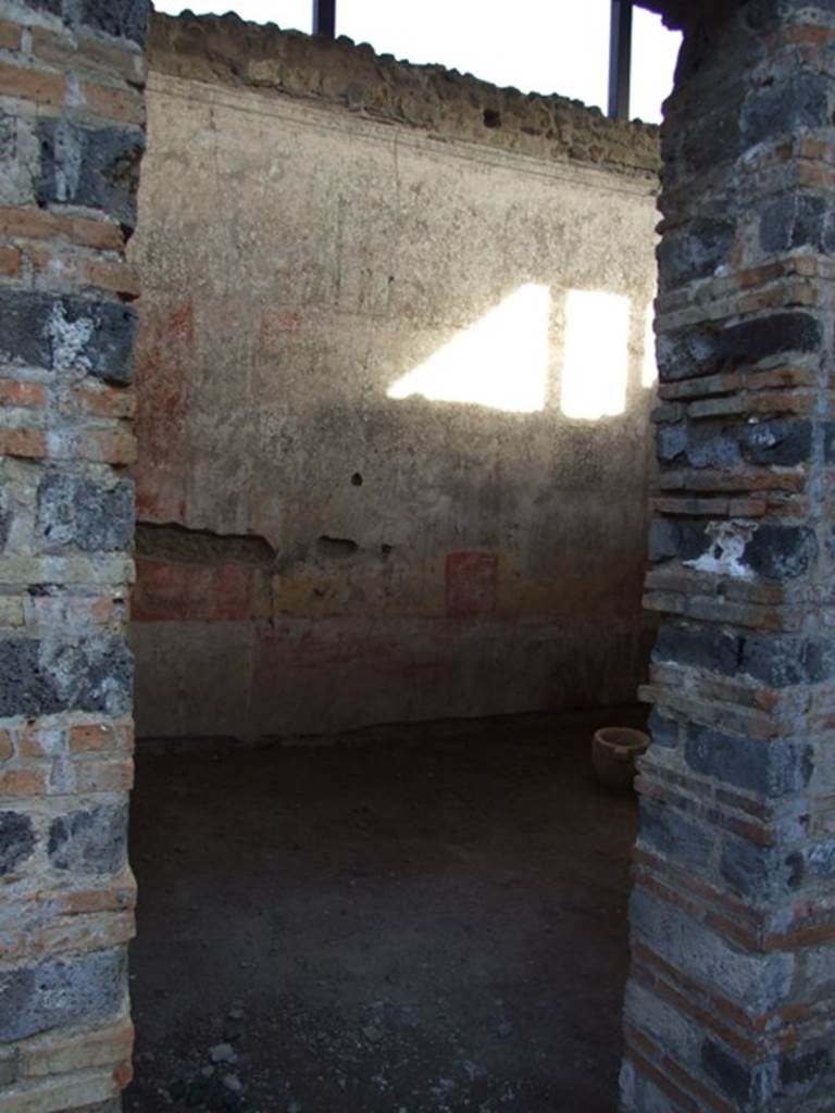 IX.5.11 Pompeii. December 2007. Doorway to room 4, looking east. This room also had a decoration of red and yellow panels, fragmented by ornate architecture. In the yellow panels were small paintings. The one on the north wall (0.51 x 0.44) showed a naked standing Bacchus, crowned with foliage, leaning on a pilaster with his left elbow, inside his elbow was his cloak. In his right hand was a short rod/staff, near to him on the ground was an amphora with a wide neck. Of the other two paintings on the east wall, the first (0.45 x 0.53) showed a Cupid, with two whips, one in each hand following a goat. The second (0.45 x 0.42) also showed a Cupid encouraging a dog to attack a rabbit. The west wall having been holed did not preserve any paintings in its panels. 
Whereas on the south, under the window, the yellow plaster that one sees above a most antique decoration (II Style) was decayed. White lozenges (diamonds) were in the red panels, in each lozenge was a painted Cupid, some with rod and pan-pipe, some with crook or with a cornucopia. In the panel of the frieze, finishing above of an elegant cornice of stucco, were painted some isolated figures, around 0.54 high. 
Beginning from the north wall, one had -
1.)  Female standing woman, with long purple robe.
2.)  Satyr crowned with reed, with greenish cloak, having a torch in his right hand and a bunch of grapes in his left hand. 
3.)  Female figure with green robe, with left hand raised to her head and holding the edge of her cloak.
4.)  Female figure with purple robe, with a garland of leaves between her hands.
5.)  Naked Satyr, with cloak around his legs, the shepherds crook in his left hand, and pan-pipe in his right.
6.)  Female figure dressed in dark green robe with a yellow tunic above, holding a lance in the left hand.
7.)  Another female figure with red robe and yellowish cloak, who had a fan in the guise of a leaf in her right hand.
8.)  Virile naked figure, except for a purple cloak that fell from his shoulders and which was wrapped around his left arm, in his right hand he held an  arrow tied to a snare, whose other end he held in his left hand.
9.)  Virile figure, badly preserved, with dark green cloak and a lance.
10.) Woman with green robe, gazing intently into a round mirror held in her left hand: the mirror did not have a long handle, but was held on the wrong  side.
11.) Another woman with a yellow robe and greenish cloak, who held a basket filled with fruit in both hands.
See Notizie degli Scavi, 1877, (p.248-9)
See BdI, 1879, (p.198-201)
