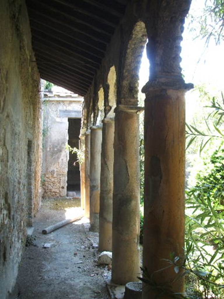 IX.7.20 Pompeii. May 2005. Looking south along east portico.
The doorway that can be seen in the left wall, leads into small room (L), a cubiculum. 
Previously this small room, room (L), would have led into a room belonging to IX.7.25.


