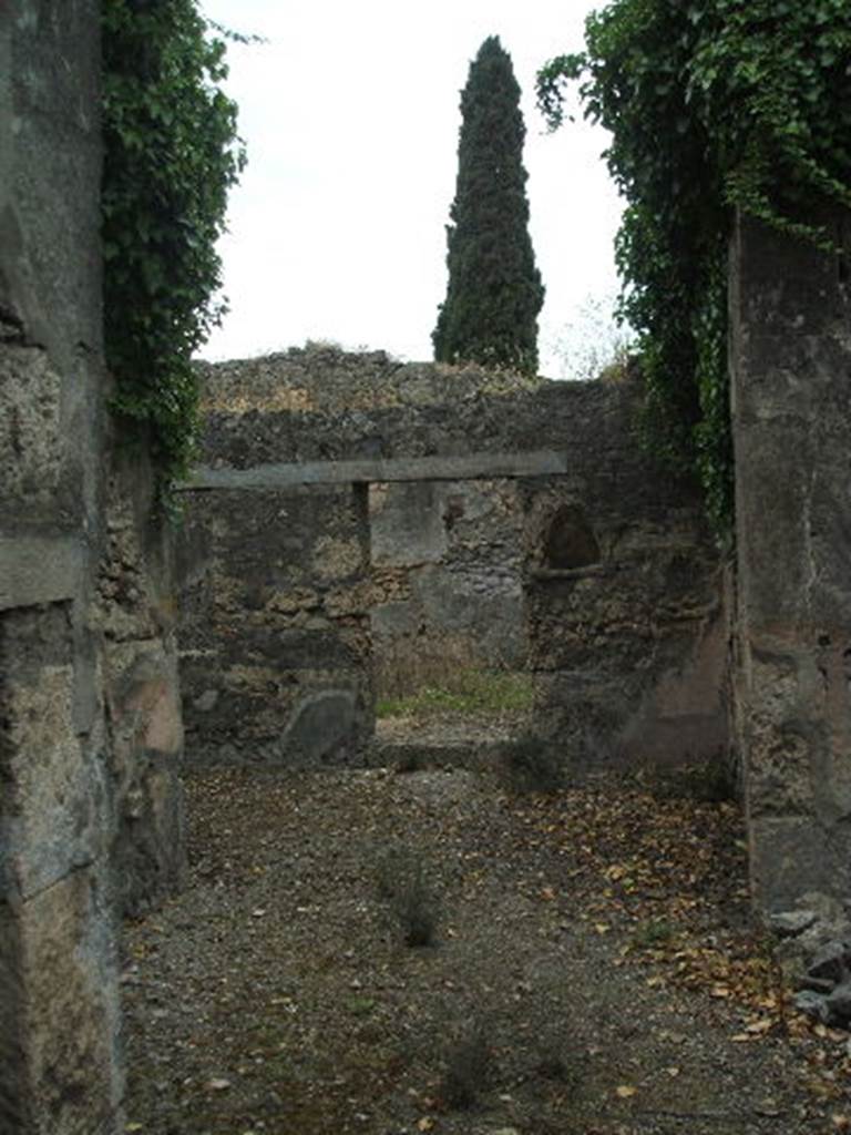 IX.9.11 Pompeii. May 2005. Looking west across atrium towards garden area, from entrance doorway. According to NdS, this small house or perhaps a hotel, was formed by a displuviate entrance hallway, four bedrooms, a dining room and a garden adjacent to it.
The atrium was entered down from the roadway by two small steps, now destroyed. It had a beaten floor with the walls covered in rough white plaster and a high zoccolo (dado) of crushed brick on the walls. In the north-east corner of the atrium was the latrine. Buried in the atrium wall, to the right of the doorway to the garden, at the height of a man, was a niche with a pointed arch, covered in white plaster and painted with the usual foliage and red flowers.
See Notizie degli Scavi, 1891, p.261.