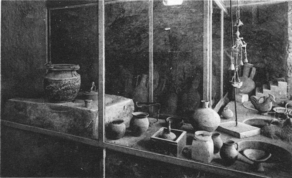 IX.11.2 Pompeii. Old postcard, about 1920, showing counter with a number of items displayed on it. The small stove has its lid in place.