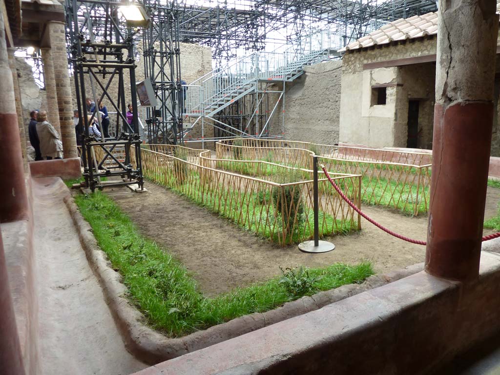 IX.12.9 Pompeii. May 2010. 
Looking south-west across peristyle/garden area 5. Room 9 can be seen under the grey metal stairway.
According to an information card in the house -
“In the garden at the centre of the triporticus, the original design of the flowerbeds was reconstructed thanks to the imprints of the fences and casts of garden plants. The garden was also decorated with a fountain which was crowned with a statue of a young boy, on which we can identify traces of original colours.”

