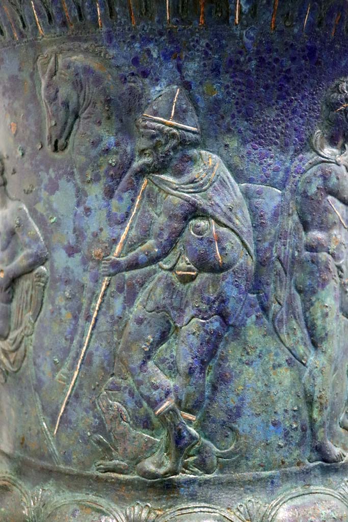 IX.13.1-3 Pompeii. February 2021.
Bronze krater with scenes in relief, found in triclinium, on display in Antiquarium, VIII.1.4.
Detail of the bearded figure holding a staff. Photo courtesy of Fabien Bièvre-Perrin (CC BY-NC-SA).