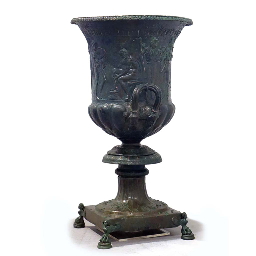IX.13.1-3 Pompeii. February 2021.
Side and rear of bronze krater with scenes in relief, found in triclinium, on display in Antiquarium, VIII.1.4.