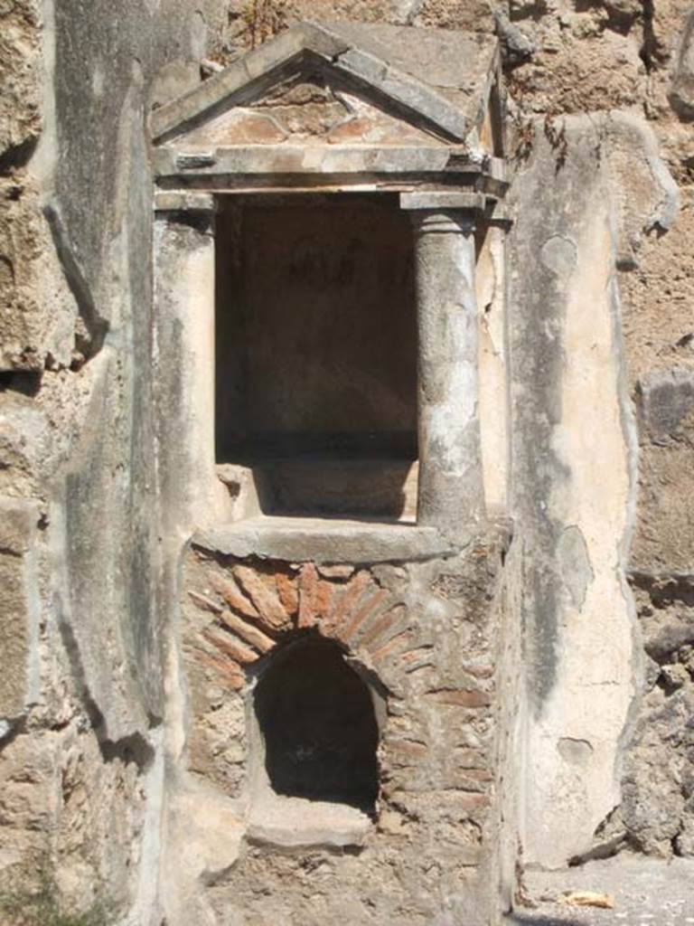 IX.14.4 Pompeii. May 2005. Aedicula household lararium shrine 32 in atrium.
According to Boyce, above a masonry base built into the north-west corner of the atrium, one Doric column and two pilasters support a roof of two pediments.
These pediments are set at right angles to each other.
The walls within were painted white with narrow green and red bands, the two tympana being red.
An arched niche is on the south side, probably for storage.
On the two walls in the shrine is a low step, on which were found three statuettes -
a herm of white marble, a terracotta bust of a male figure, and a second bust of a male figure.
Also found within the shrine were – a terracotta lamp, a coin of Caligula, a small terracotta altar in the form of a vase, and an iron container for coals.
Found in the niche at the base of the aedicula was a terracotta lamp fitted with a ring.
Not. Scavi, 1911, 311, with photo on p.333.
See Boyce G. K., 1937. Corpus of the Lararia of Pompeii. Rome: MAAR 14. (p.30, no.67 and Pl.29,3).