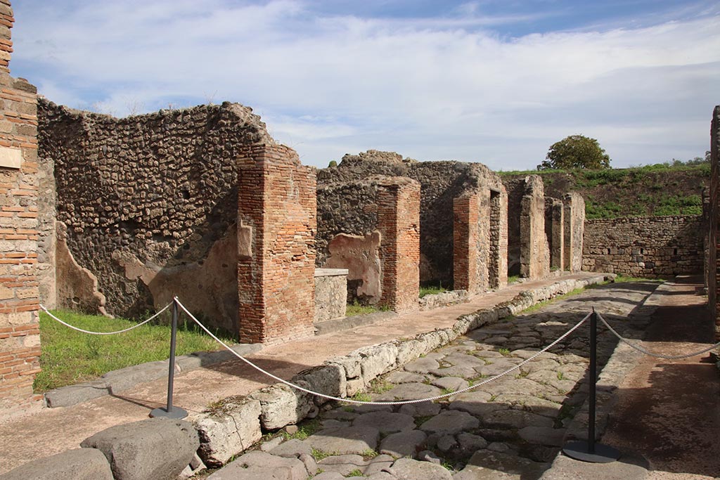 Unnamed vicolo/continuation of Via degli Augustali, between IX.6 and IX.7, Pompeii. October 2024. 
Looking north-east along IX.6 on north side of roadway. Photo courtesy of Klaus Heese.
