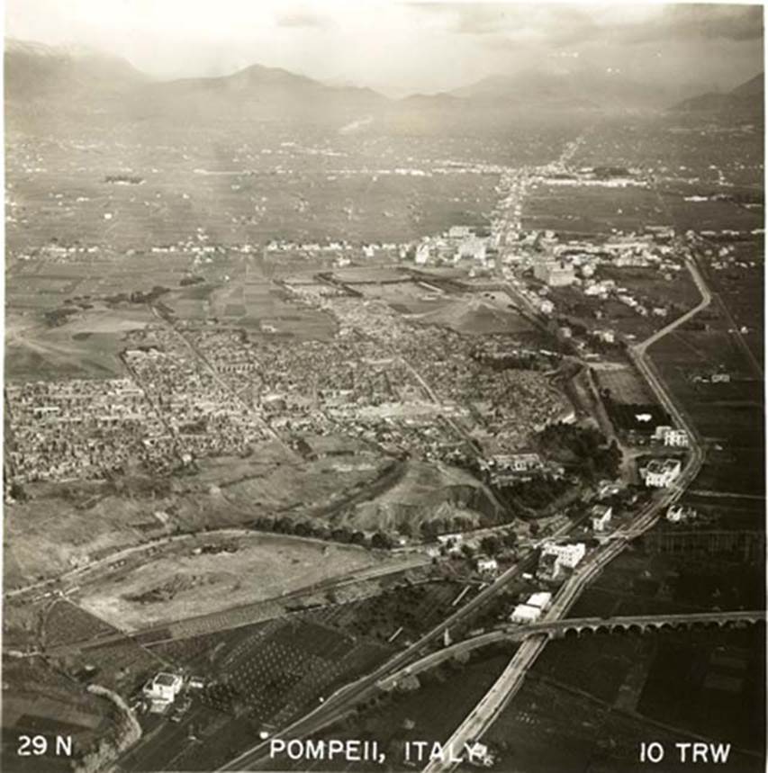 1950s aerial view. Looking east. The station from Naples or Sorrento would be along the track near a small white building (above the letter Y of ITALY on the lower side of the photo). Slightly higher than the small white building would be an unexcavated area, including the area of the Suburban Baths. The larger building would be the Imperial Villa/Antiquarium, on the south side of the Porta Marina. From the station, the curving Via Villa dei Misteri can be seen. Photo courtesy of Rick Bauer.
