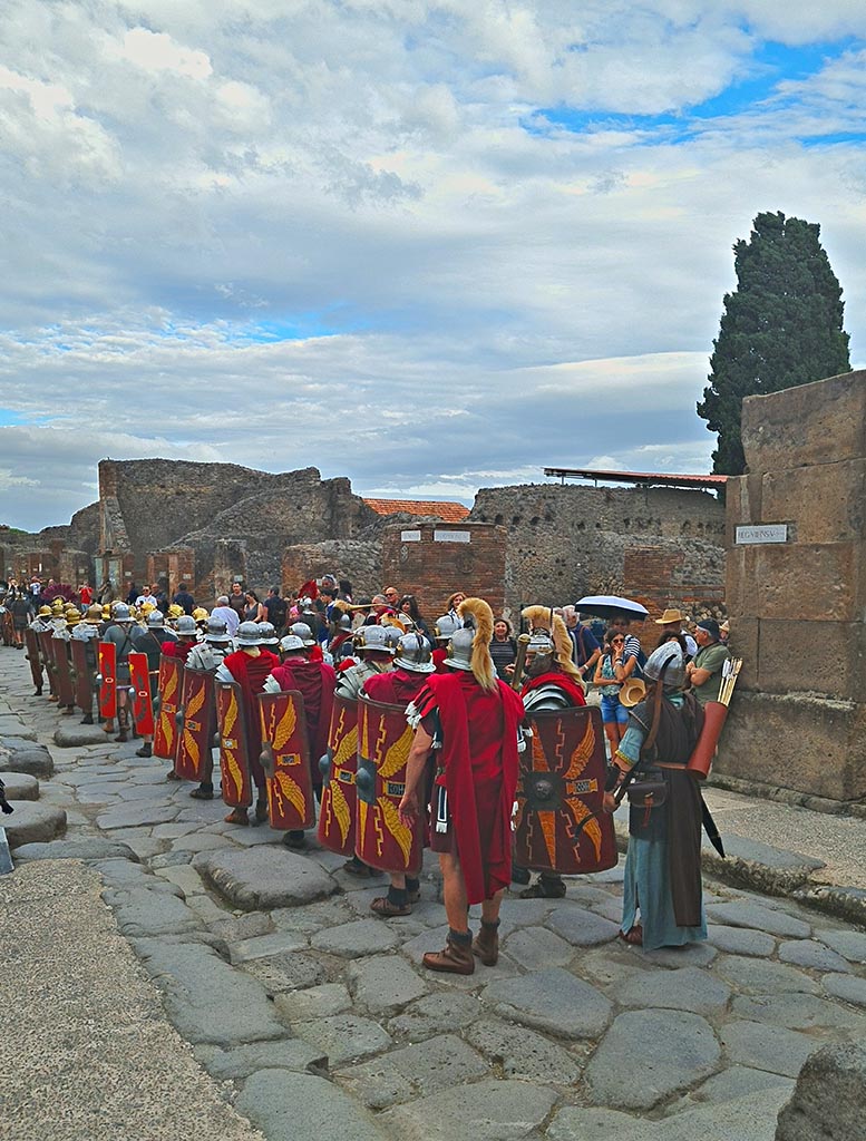 Via dell’Abbondanza, south side, Pompeii. 28th September 2024. Legionaries and archer marching.
Looking south-east towards junction with Via dei Teatri, during “Ludi Pompeiani” event. Photo courtesy of Giuseppe Ciaramella.

