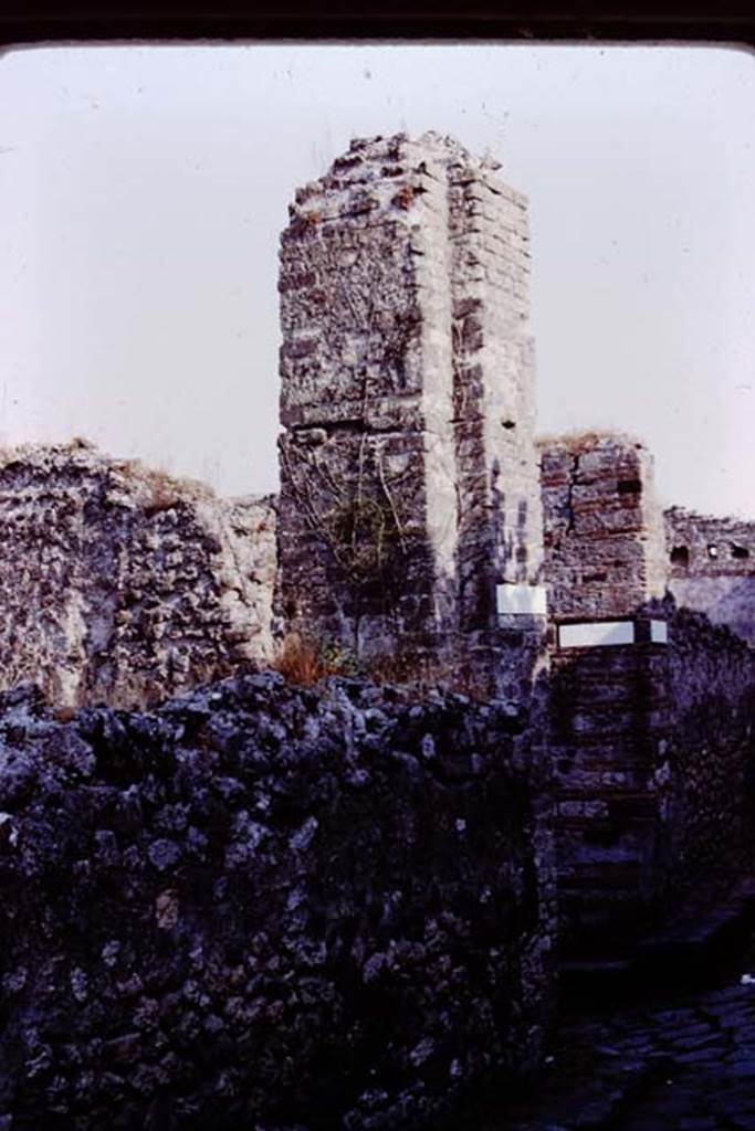 Vicolo dei Dodici Dei, Pompeii. 1980. Looking south to junction with Vicolo della Parete Rossa, and water tower/castle on corner of VIII.5. Photo by Stanley A. Jashemski.   
Source: The Wilhelmina and Stanley A. Jashemski archive in the University of Maryland Library, Special Collections (See collection page) and made available under the Creative Commons Attribution-Non Commercial License v.4. See Licence and use details. J80f0218
