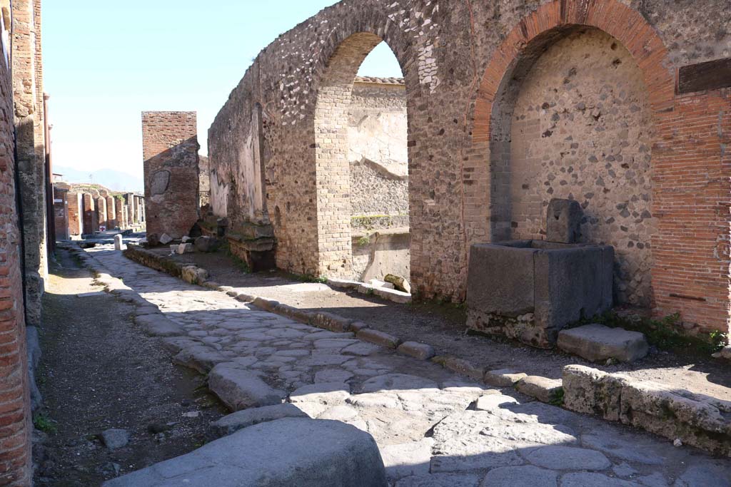 Vicolo dei Soprastanti, south side, December 2018.
Looking east along VII.8, north wall of Forum, and fountain at side of entrance to the Forum. Photo courtesy of Aude Durand.