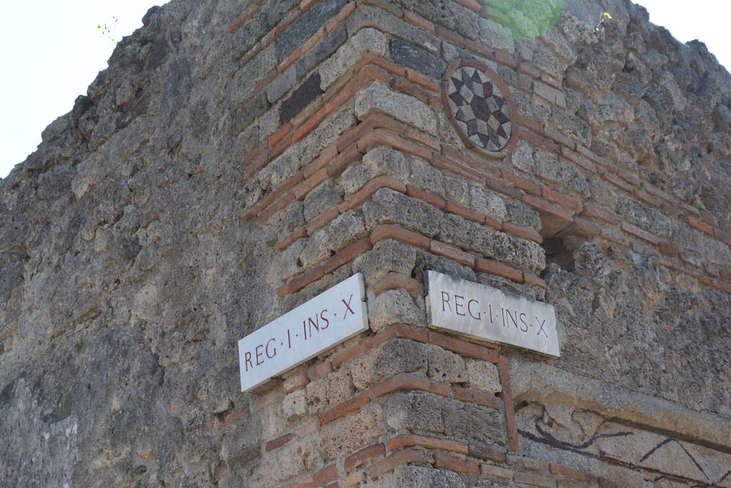 Vicolo del Citarista, April 2017.
Corner of insula I.10, Vicolo del Menandro, on left, and coloured terracotta plaque above doorway of I.10.9, in Vicolo del Citarista, on right.
Photo courtesy Adrian Hielscher.
