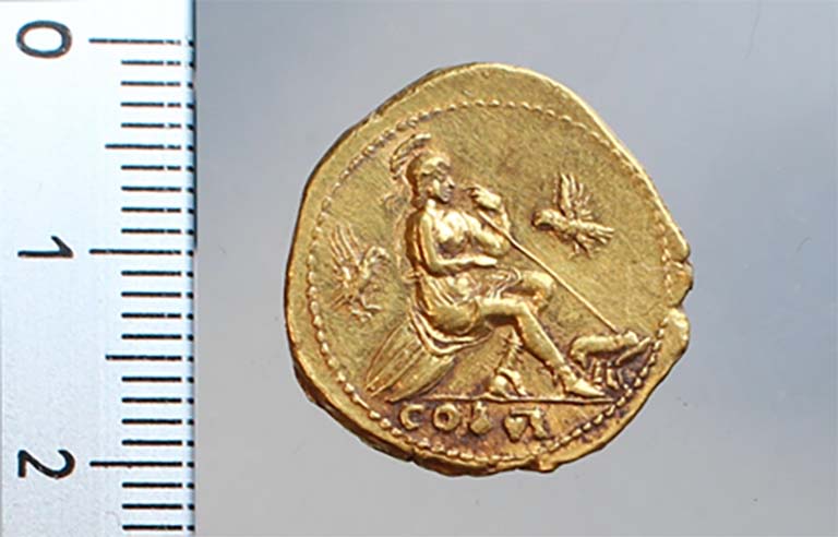 Aureus of Vespasian. One of the gold coins, abandoned in the middle of the skeletons.
77-78 AD Personification of Rome, the left foot, inwards, rests on a helmet.
At the feet, on the right, the she-wolf breastfeeding Romulus and Remus.
Photo © S. Zanella/S. De Rosa – EFR.
Aureus de Vespasien. Une des monnaies en or, abandonnée au milieu des squelettes.
77-78 ap. J.-C. Personnification de Rome, le pied gauche, vers l’intérieur, repose sur un casque.
Aux pieds, à droite, la louve allaitant Romulus et Remus.
Photo © S. Zanella/S. De Rosa – EFR.
See Pompei- le secteur de la Porte d’Herculanum à Pompéi Centre Jean Bérard