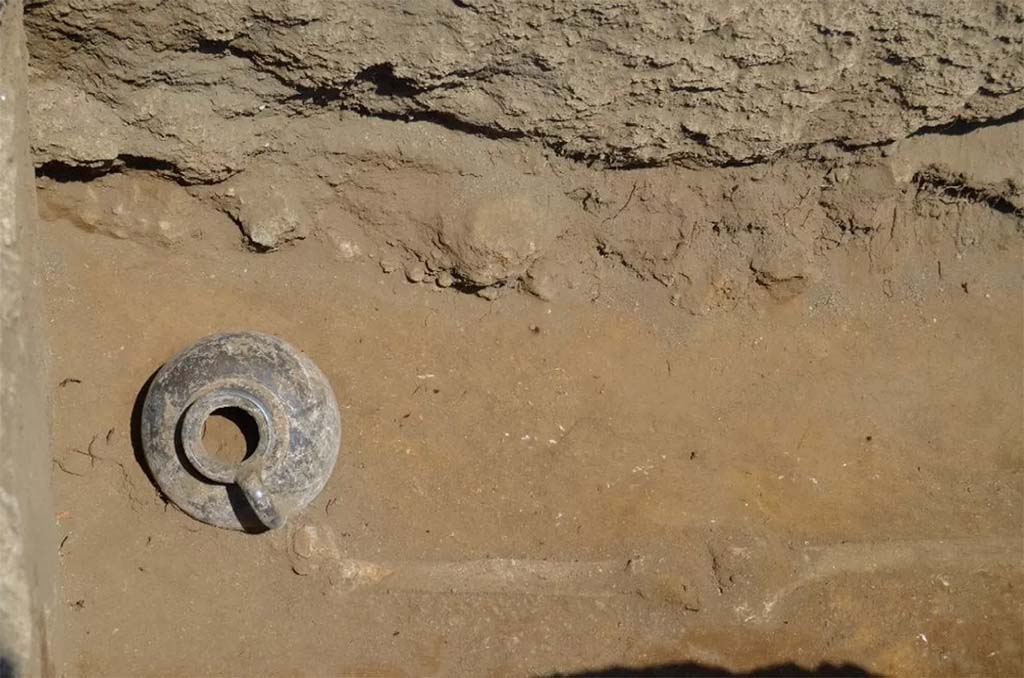 HGE32A Pompeii. June 2016. Tomb of a Samnite Man. The black painted jug next to the right foot of the deceased Samnite
La brocca a vernice nera accanto al piede destro del defunto sannita
Photograph © Parco Archeologico di Pompei.