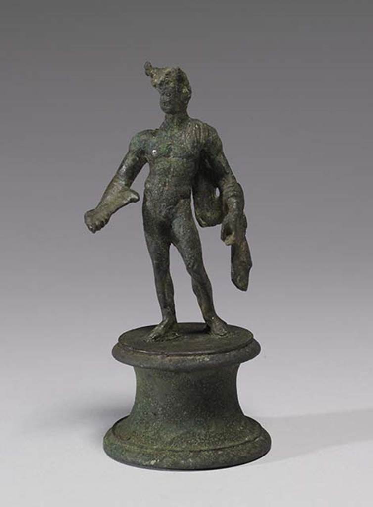 Boscoreale, Villa rustica in fondo D’Acunzo. Room 12, lararium. 
According the The Walters Art Museum, this is a bronze statuette of Mercury, front view.
According to Della Corte, this statuette seemed to represent a faun, (0.12 high) naked except for a goat skin between the left shoulder and corresponding elbow.
He has what may be a syrinx? (pan-pipe) held lowered in his right hand. 
Upon his head were two projections on the sides of the forehead, apparently horns, but they were seriously damaged. 
See Notizie degli Scavi di Antichità, 1921, p. 441. According to Stefani, the different. and more plausible interpretation proposed by others is an image of Mercury.
See Stefani G., 2000. In Sylva Mala, Bollettino del Centro Studi Archeologici di Boscoreale, Boscotrecase e Trecase XII, p. 11-16 and note 44.
Photo courtesy of The Walters Art Museum, Baltimore. Inventory number 54.748.
http://thewalters.org/
Creative Commons Attribution-ShareAlike 3.0 Unported Licence
