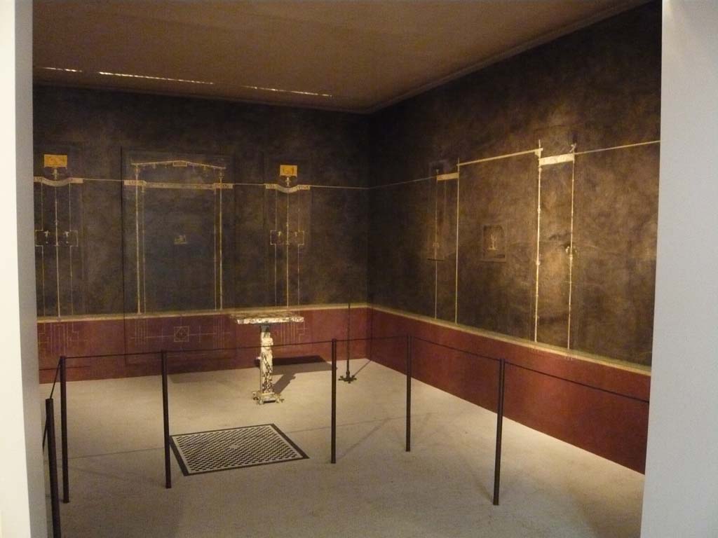 Villa of Agrippa Postumus, Boscotrecase. December 2010. Room 15, looking towards the north-east corner and east wall of cubiculum.
Photograph taken at Metropolitan Museum New York. Photo courtesy of Buzz Ferebee.
According to NdS,
“Room “No. 15”, the first cubiculum, had a chessboard mosaic of 0.92m sides closed in a broad black band and containing a net of nine hexagons with black outlines in the centre of its floor of white mosaic: and, in the threshold was a more simple geometric black pattern. Of the elegant and sober wall decorations, on a black background above a dark-red dado/plinth, sparing a detailed description, I reproduce fig. 7 (below):