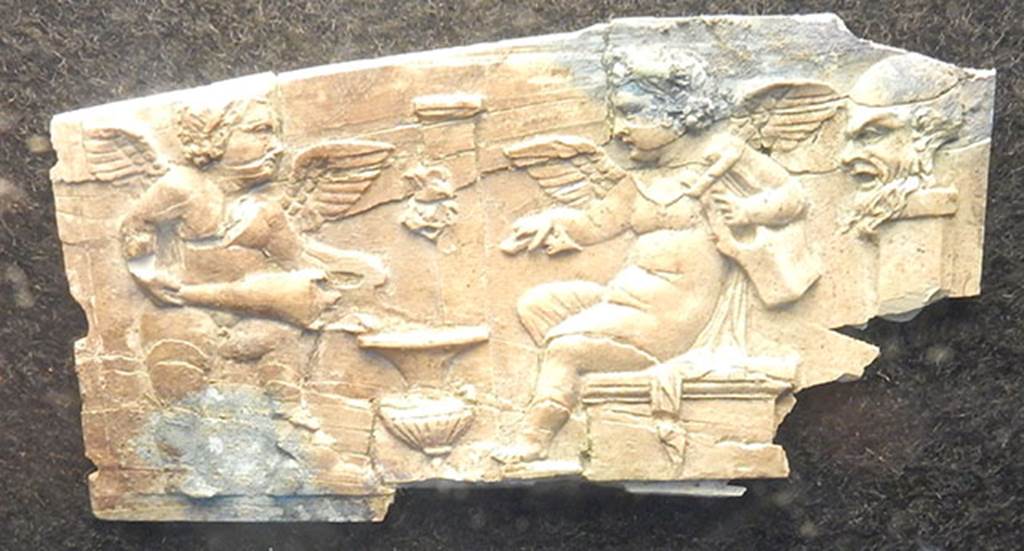 Villa Rustica di Marcus Livius Marcellus. Ivory plaque found in a cubiculum. On the right is a pilaster on which is a bearded head in relief (Silenus?).
Left and centre are two cupids, one holding a lyre and the other pouring wine from an amphora into a krater which is near a fountain with a mask on a pilaster.
Photo courtesy of Buzz Ferebee.
See Notizie degli Scavi di Antichit, 1929, p. 185, fig. 7.
