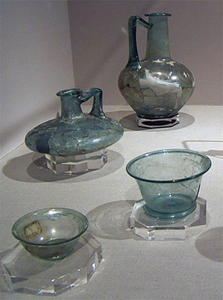 Gragnano, Villa rustica in Località Carmiano, Villa A. Glass items found in the villa.
Stabiae Antiquarium, inventory numbers
63519 tall glass bottle with flared rim and handle, from room 9, reassembled form fragments.
63408 taller light green cup, from room 6, reassembled from fragments.
63395 lower light green cup with splayed rim, from room 6, found intact.
61407 flat bottle is from Santa Maria La Carita, Villa Petraro.
See Bonifacio G., 2004. In Stabiano: Exploring the Ancient Seaside Villas of the Roman Elite. Castellamare: Nicola Longobardi, p. 133.