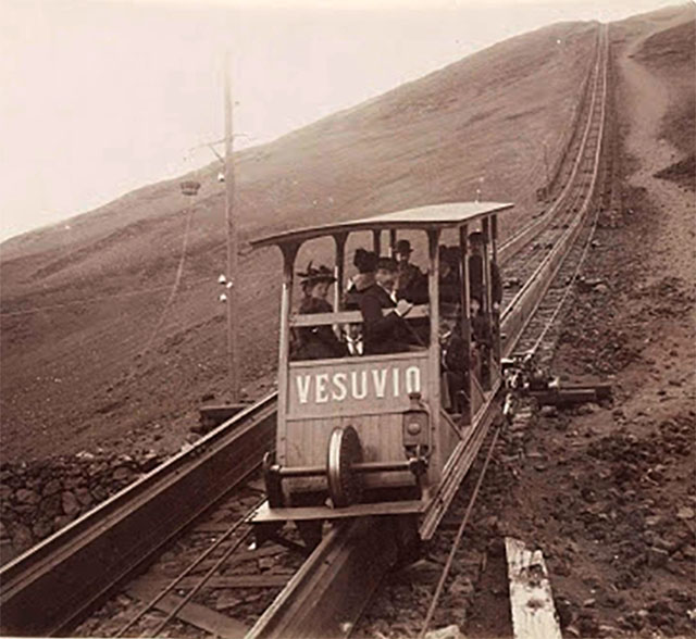 Vesuvius Funicular car Vesuvio. Undated black and white photo but must be between 1889 and 1904.
There was a longitudinal wooden sleeper on the top of which was carried a single rail. 
The cars had a double flanged wheel at each end which ran on this rail. 
In addition, there were two angled rails, one fixed to each side of the sleeper at its base. 
The cars had wheels mounted from their floors which engaged on these side rails and kept the cars upright. 
Each track had two continuous cables carried on pulleys which were fixed to each side of the car.

