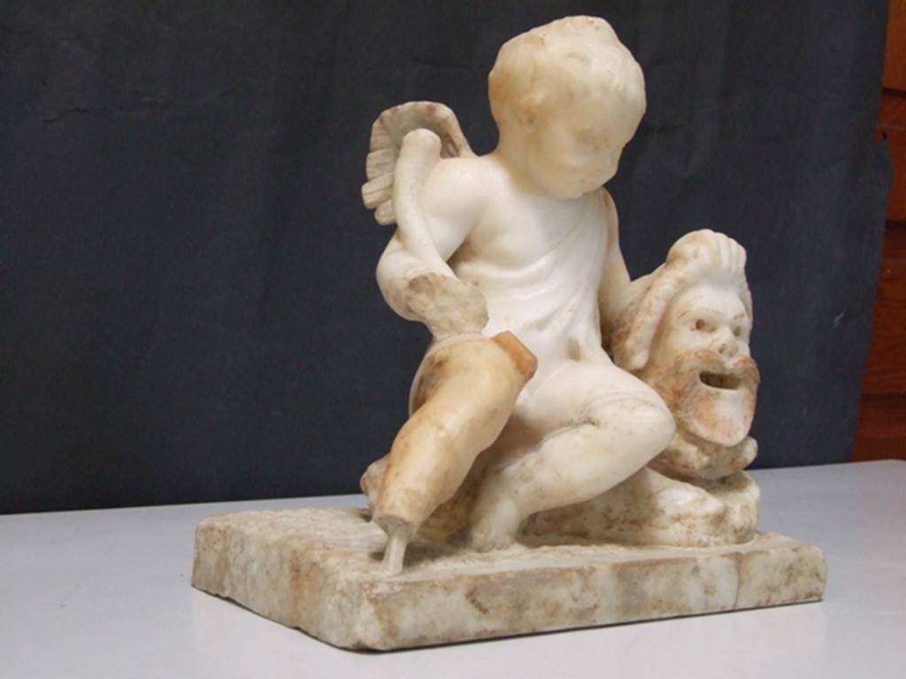 II.2.2 Pompeii. March 2009. Room “l”, garden. White marble statuette of a cupid with a mask.
Found above the marble steps in the nymphaeum at the top of the lower euripus in the garden in 1920.
SAP inventory number: 20513.