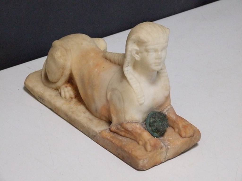 II.2.2 Pompeii. March 2009. Room “i”. White marble statuette of Sphinx, with a face of a bronze gorgon between the front legs. Found on the north side of the upper euripus in the garden in 1920. SAP inventory number 2930.